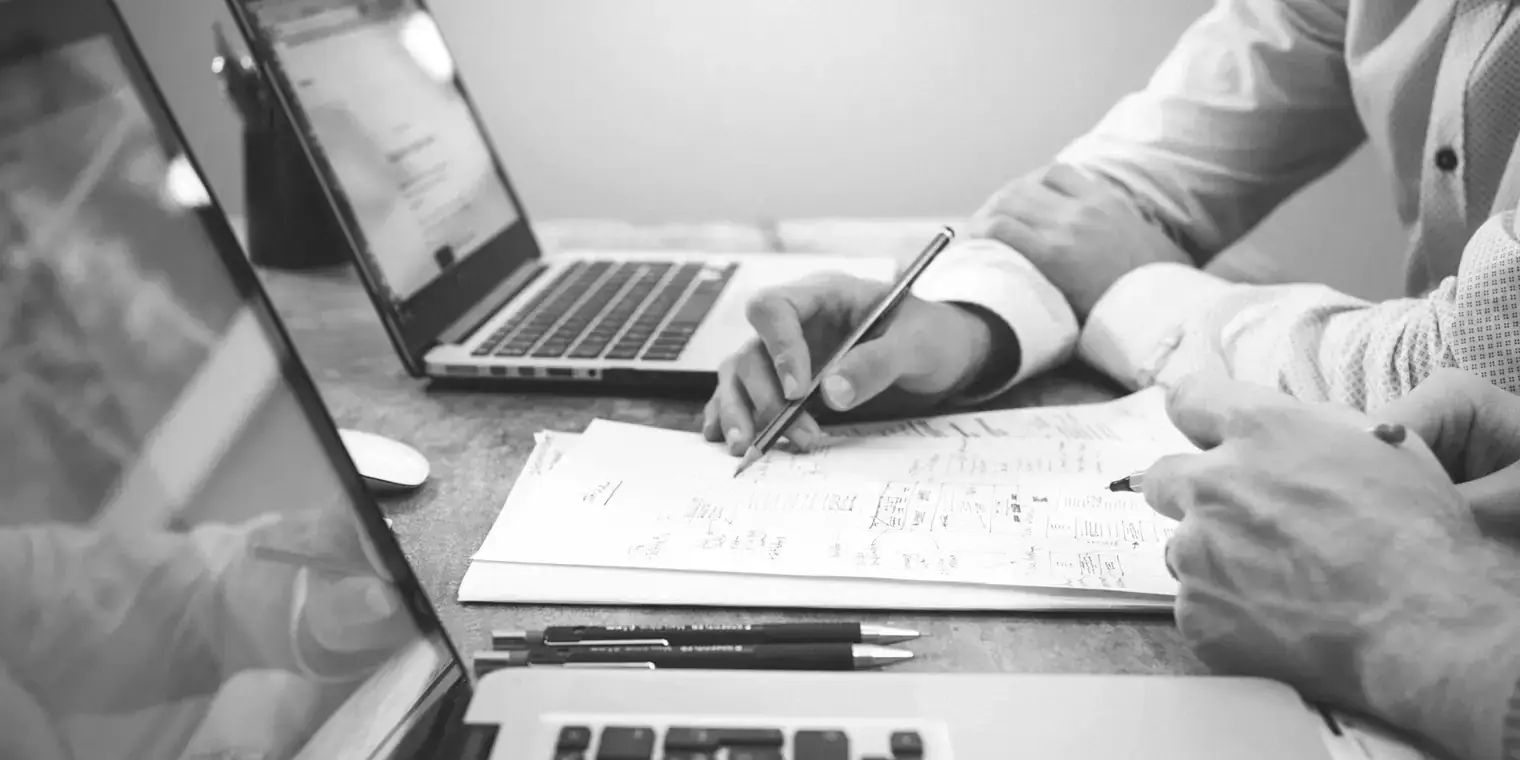 Dos personas comparando presupuestos con portátiles y cuadernos sobre una mesa