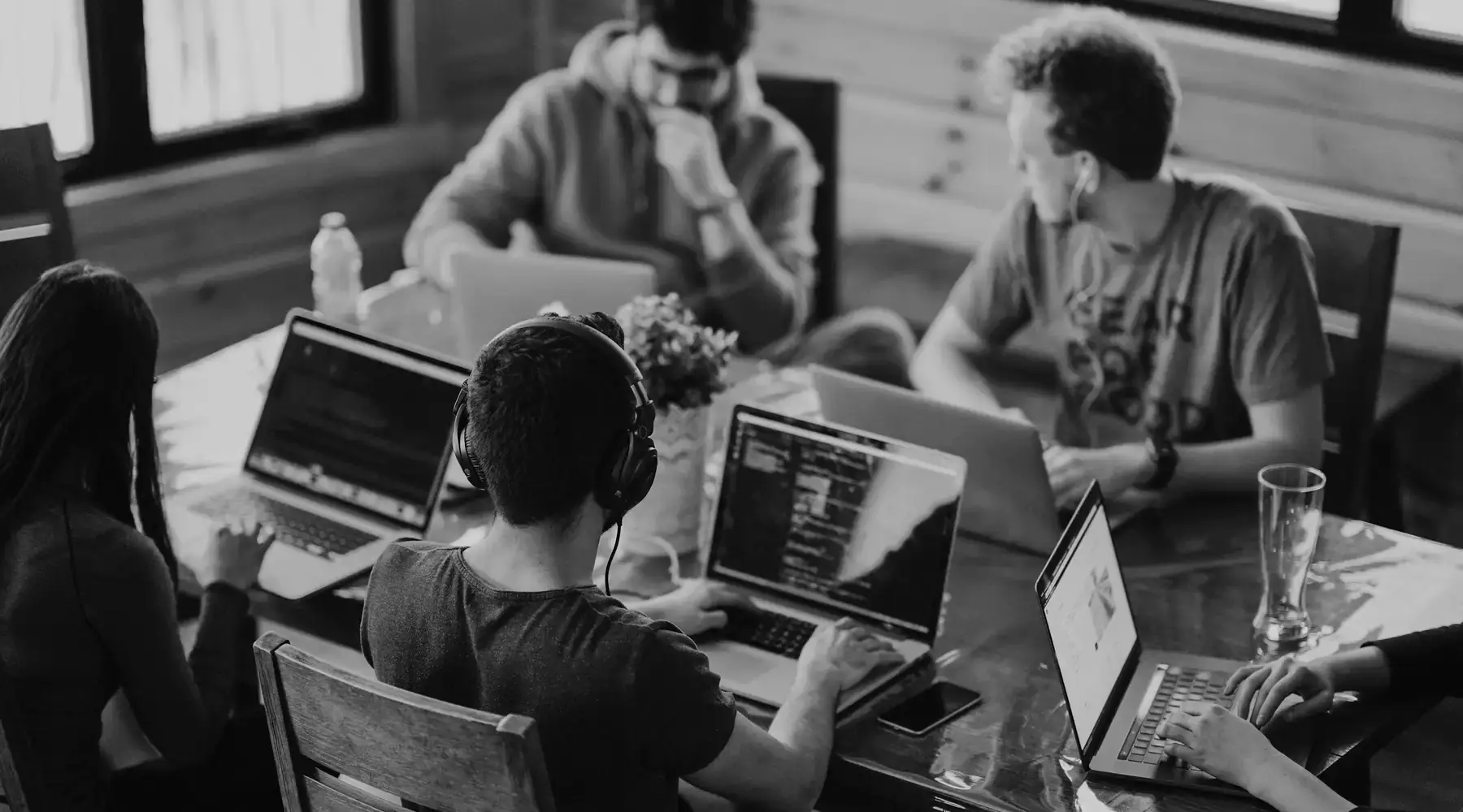 Equipo trabajando alrededor de una mesa larga con portátiles y cuadernos