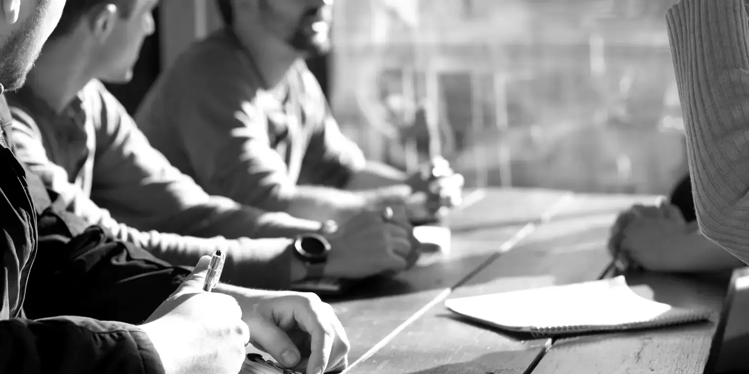 Reunión de trabajo alrededor de una mesa con portátiles y documentos