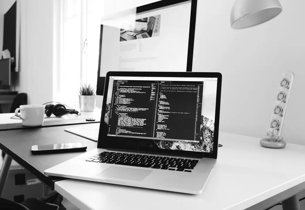 Portátil abierto sobre una mesa blanca mostrando el código de una página web
